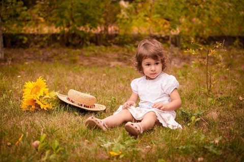 Little girl with sunflowers in a stetson on the garden