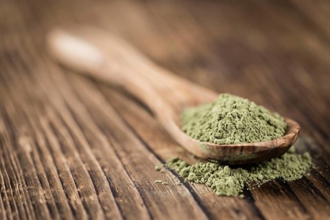 Portion of Stevia leaf powder (detailed close-up shot) on rustic wooden background