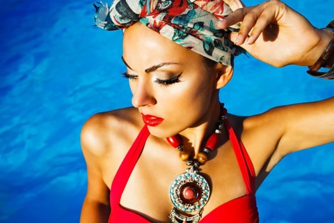 Beautiful fashionable woman near the pool wearing colored turban