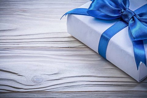 Present box with blue satin tape on wooden board celebrations concept