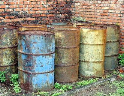 Corroding oil drums in a deserted building pollute the ground