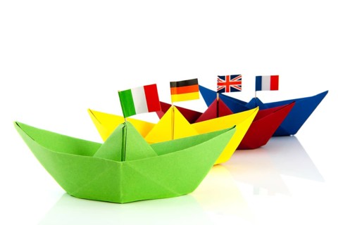 Colorful folded paper boats with European flags isolated over white background