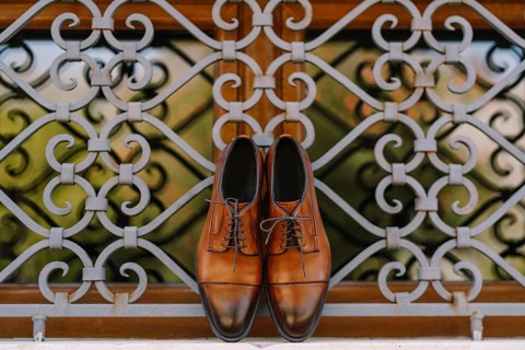 Stylish brown men's shoes made of genuine leather by the window with a metal lattice.