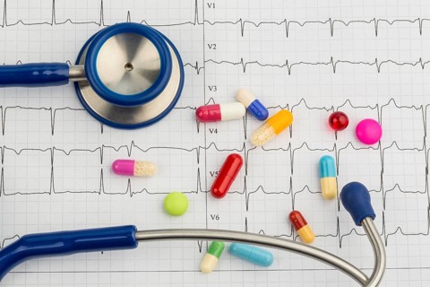 Several tablets lie on an ECG. Symbolic photo for cardiovascular diseases