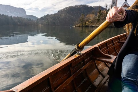 Young woman using paddle on a wooden boat, Lake Bled Slovenia rowing on wooden boats on a sunny day