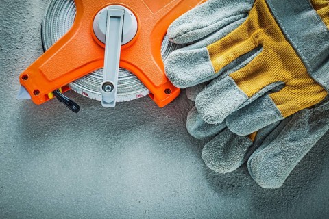 Safety gloves measuring tape on concrete background