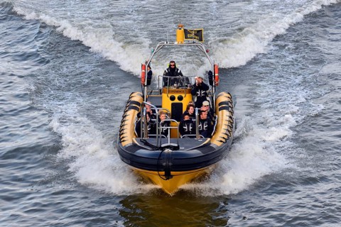 Speedboat with several people travelling at high speed across the water, London, London region,