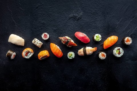 Sushi overhead flat lay shot. Rolls, maki, nigiri on a black slate background, Japanese food.