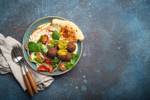 Middle Eastern Arab meal with fried falafel, hummus, vegetables salad with fresh green cilantro and