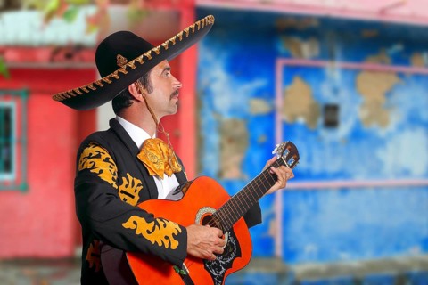 Charro Mariachi singer playing guitar in Mexico houses background