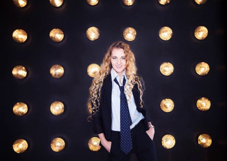 Blond happy woman wearing classical suit over golden shining background