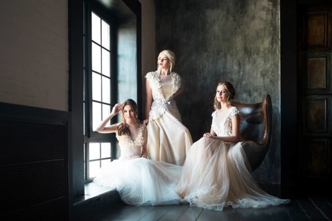 Three young women near window wearing wedding dresses