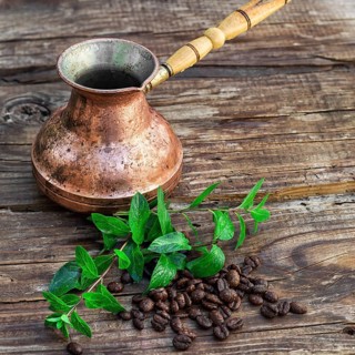 Vintage copper Turk on wooden background covered coffee beans with mint petals