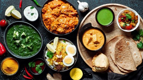 Indian cuisine dishes: tikka masala, paneer, samosa, chapati, chutney, spices. Indian food on dark