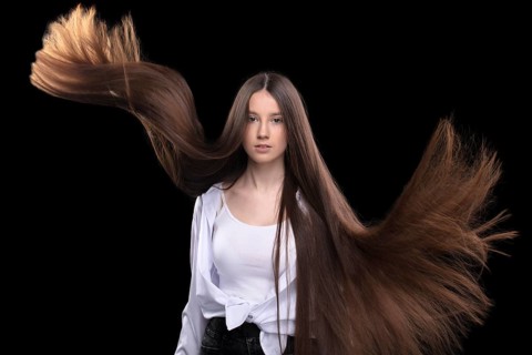 Beautiful brunette with long flying hair on a dark background
