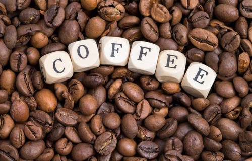 The photo shows roasted coffee beans with wooden letters
