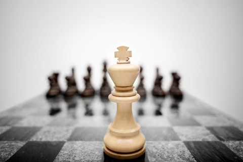 The expressive photo of the chess king standing in front of the set of pieces of a different colour