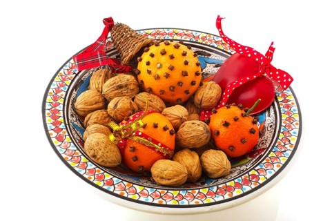Orange with cloves and walnuts on bowl isolated over white
