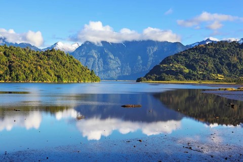Stony shallows. A wonderful day on the river. Snow-capped mountains reflected in the smooth water.