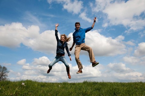 Happy jumping couple outdoor in the fields