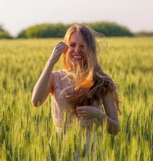 Portrait of a laughing girl with matted hair in a wheat field at sunset