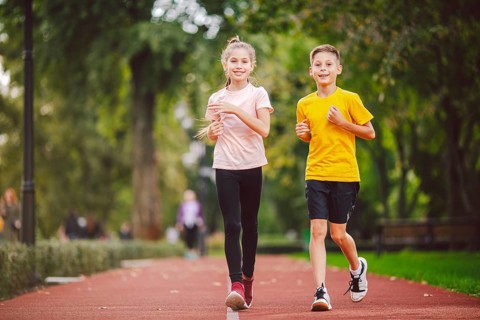 Sports and fitness in adolescence. Caucasian twins boy and girl run on the jogging track in the