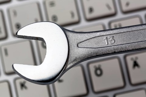 A spanner as a tool on a computer keyboard. Symbolic photo for data protection, online crime, and