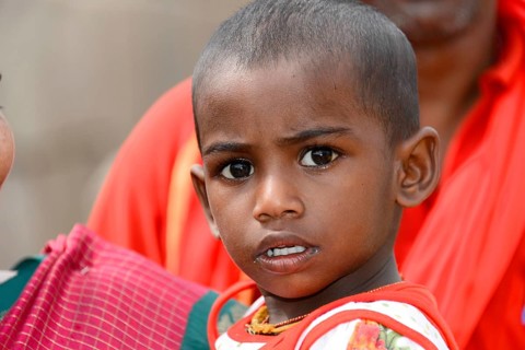 Coastal temple of Mahabalipuram, Mamallapuram, A child in red clothes with a curious and serious
