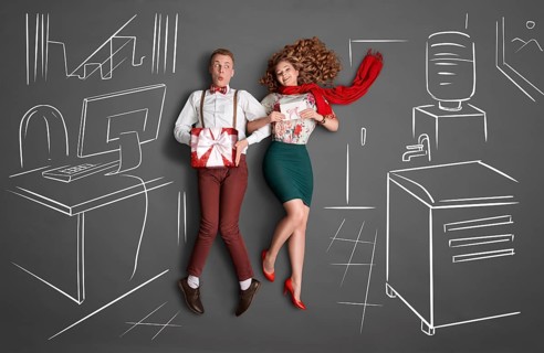 Happy valentines love story concept of an office romance. Young couple at work smiling at each