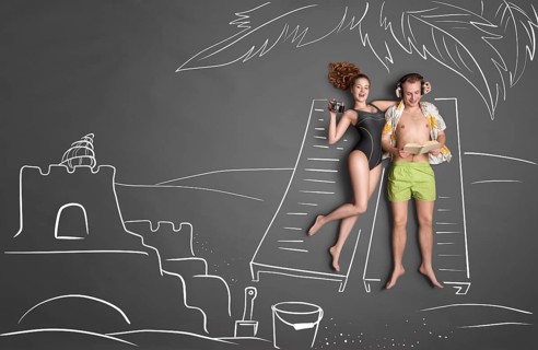 Love story concept of a romantic couple against chalk drawing background. Male lying on sun lounger