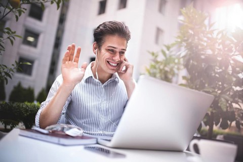 Happy handsome businessman looking at computer screen while typing something on laptop keyboard