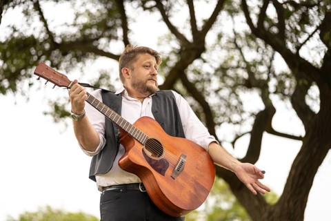 Musician gesturing while singing and playing guitar