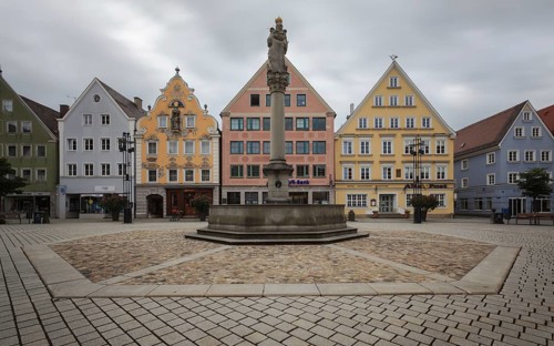 An empty market square with a statue surrounded by pastel-coloured historic buildings, Old Town
