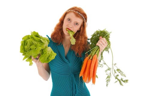 Young woman eating vegetables for diet isolated over white background