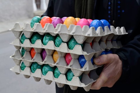 Person holding several stacks of coloured eggs for Easter
