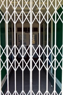 A shop is closed by a scissor gate. Symbol photo for shop opening hours