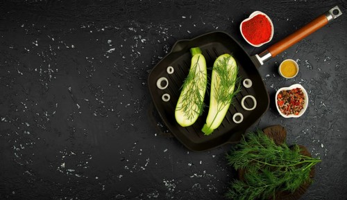 Fresh green zucchini in a pan on a dark table. The view from the top. Copy space