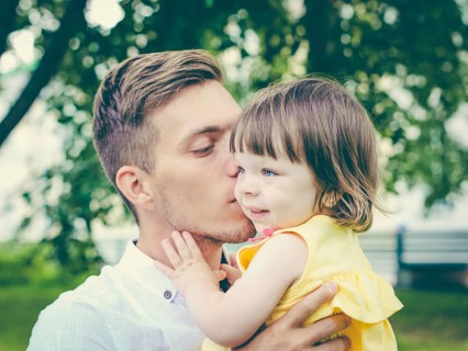 Close up of father holding his crying daughter. Dad kissing his little daughter