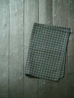 Dark wooden table with balck and white dark linen kitchen towel or textile napkin flat lay. Dark