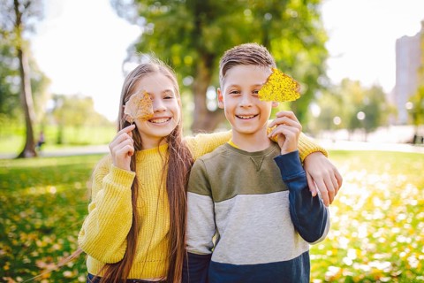 Friendship between siblings. Siblings together outside with bright coloured background. Kids autumn