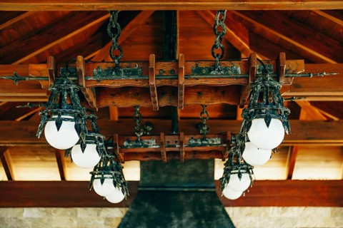 A huge wrought iron chandelier with round white balls. Metal pendant chandelier in the knight's