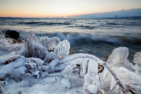 Ice-covered shore at sunrise with moving water and warm light, Hörnle, Constance, Lake Constance,