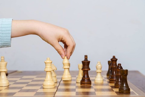 Close-up of a child's hands playing chess with a white background and copy space
