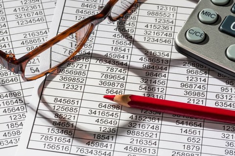 A calculator lies on the figures of a balance sheet and statistics. Symbol photo for turnover,