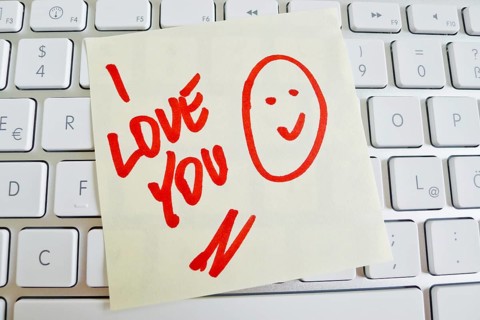 A note lies on the keyboard of a computer as a reminder: I love you Austria