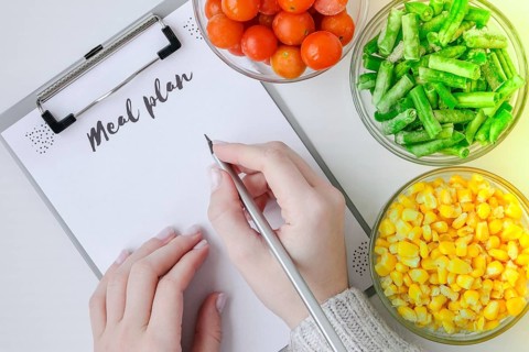 Meal plan. Three Bowls of frozen vegetables food of yellow corn, green beans, red tomatoes. Colors