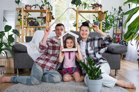 Traditional family with child are enjoying new home, sitting on the sofa and holding the roof.