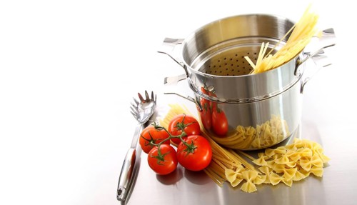 Stainless steel pot with uncooked pasta and tomatoes