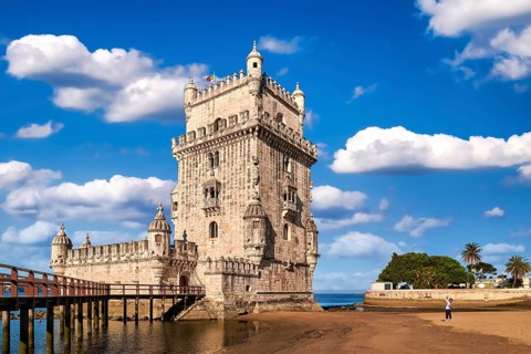 Belem tower and wooden bridge to it, Lisbon, Portugal at blue summer day sky with clouds. Medieval
