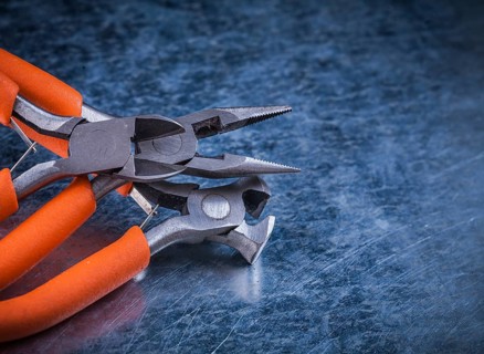Composition of insulated electric pliers nippers on scratched metallic background
